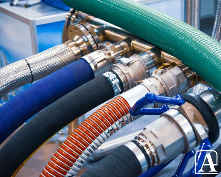 Amiflex industrial hoses in multiple colors and textures, securely connected to metal fittings with a visible blue valve in a manufacturing workspace