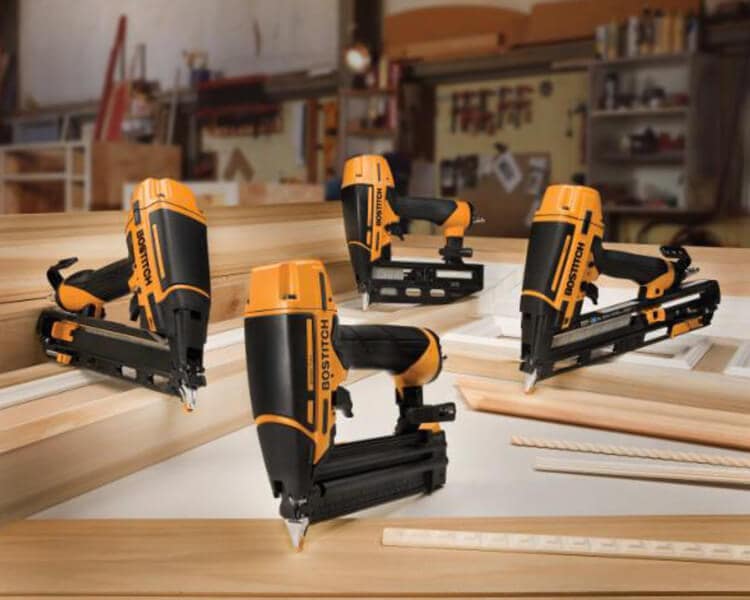 A range of Bostitch nail guns arranged on a table, demonstrating their various angles and uses for professional construction