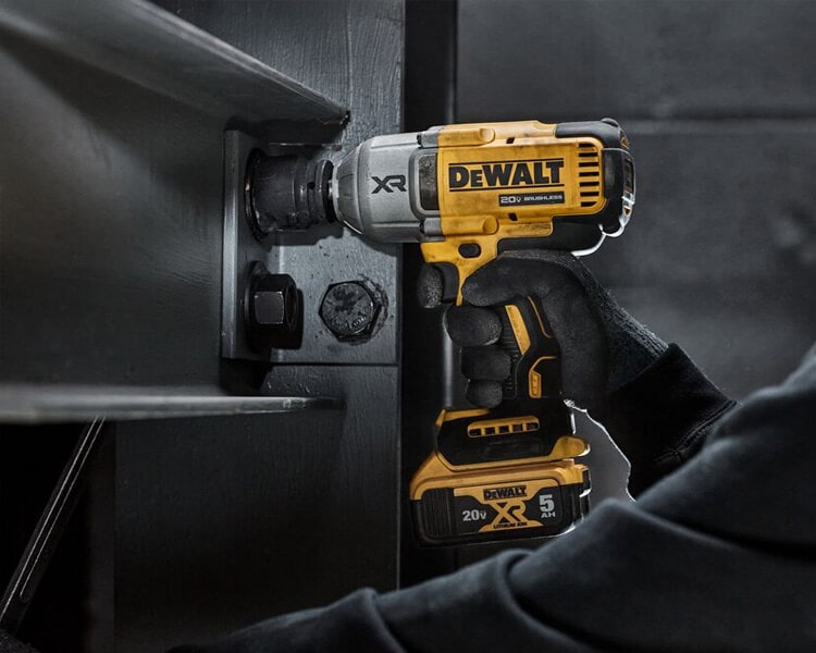 Construction worker using a Dewalt XR impact drill to fasten a bolt into an I-beam, showing the tool’s heavy-duty performance