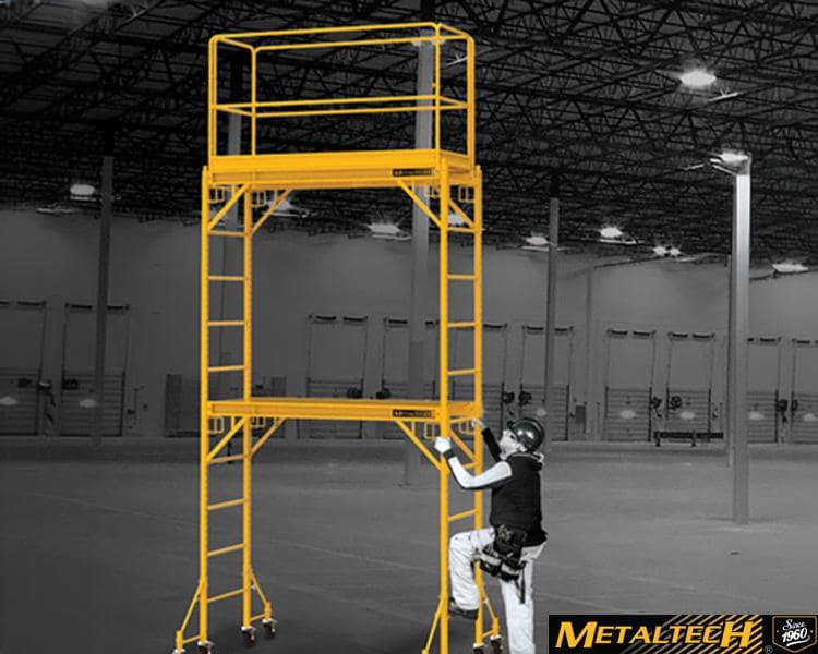 Metaltech worker standing on a ladder inside an industrial building, surrounded by metal structures and machinery, showcasing industrial expertise