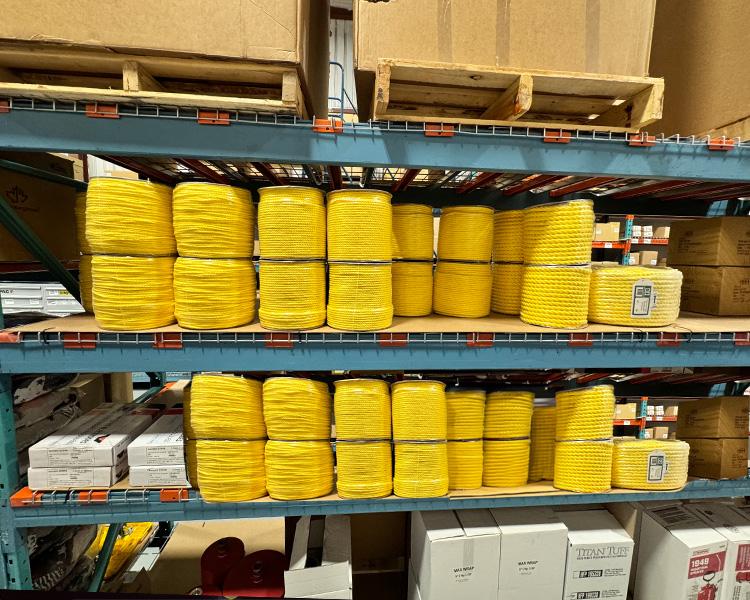 Yellow cordage and ropes neatly organized on warehouse shelves, ready for purchase. Ideal for industrial and construction use.