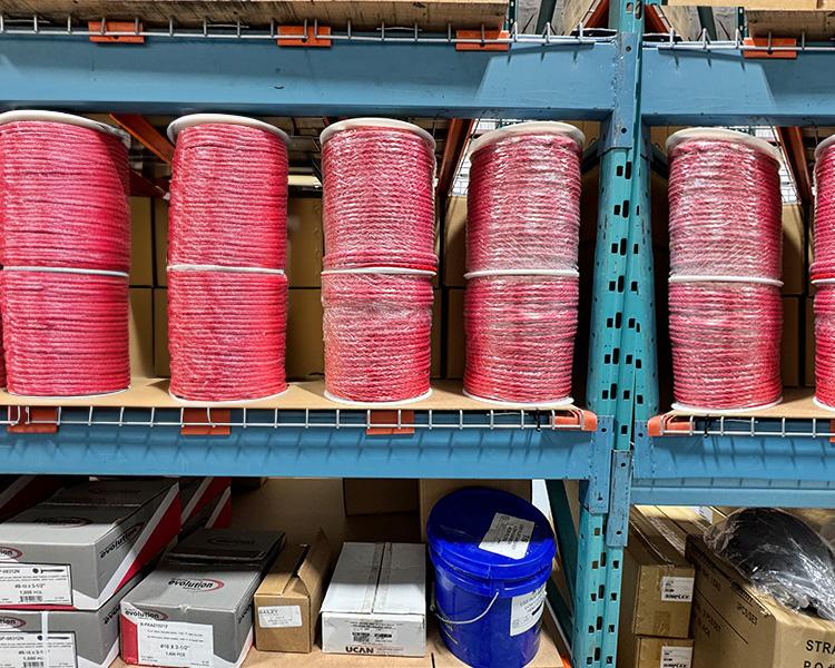 Red ropes neatly arranged on warehouse shelves, perfect for heavy-duty applications and construction.