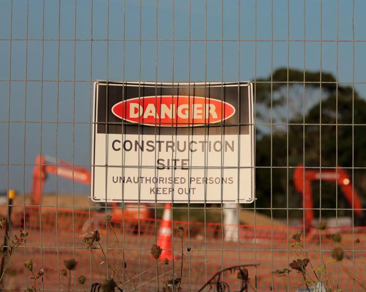A VisionMarker warning sign attached to a chain link fence, indicating potential danger and ensuring safety in a work environment.